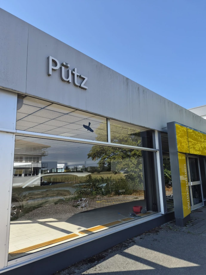 Verschmutzte Glasflächen und lackierte Blech-Fassadenverkleidung am Autohaus Pütz in Bad Wörishofen